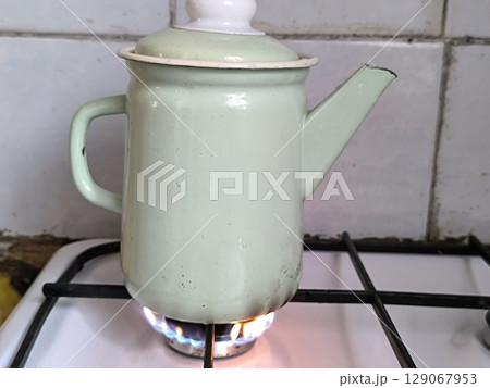 Close up of metal kettle on gas stove in kitchen. Close up of metal kettle on gas stove in kitchen. 129067953