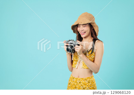 Happy travel asian tourist woman camera vacation smile holding film camera, wearing summer floral outfit and straw hat, ready for a exciting travel holiday, headshots isolated studio blue background Happy travel asian tourist woman camera vacation smile holding film camera, wearing summer floral outfit and straw hat, ready for a exciting travel holiday, headshots isolated studio blue background 129068120
