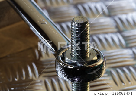 Tightening Nut On Bolt With Chrome Spanner 129068471