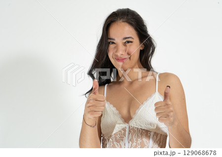 Young latin woman showing thumbs up signalling approval 129068678