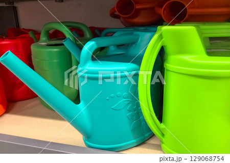 Colorful watering cans arranged on a store shelf for gardening enthusiasts 129068754