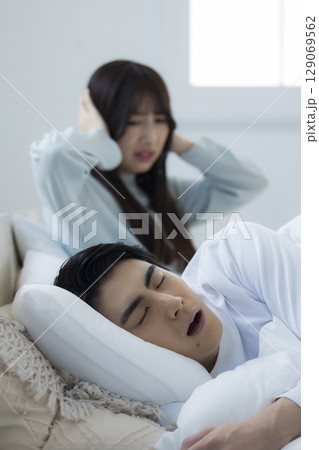 ベッドでいびきをかきながら眠る若い男性 ベッドでいびきをかきながら眠る若い男性 129069562