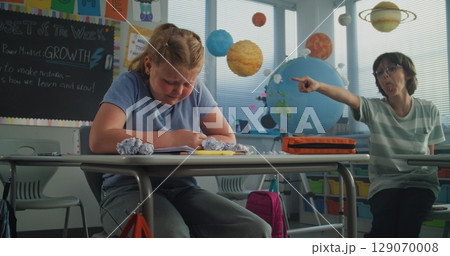 Depressed Primary School Girl Sitting at Desk While Aggressive Classmates Abusing Her Depressed Primary School Girl Sitting at Desk While Aggressive Classmates Abusing Her 129070008