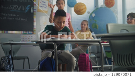 Stressed Primary School Boy Sitting at Desk While Classmates Abusing and Bullying Him 129070071