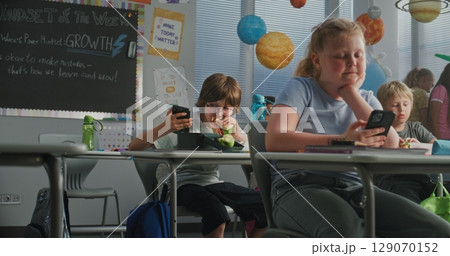Primary School Children Eating Sandwiches, Using Smartphones and Talking with Each Other During Break Primary School Children Eating Sandwiches, Using Smartphones and Talking with Each Other During Break 129070152
