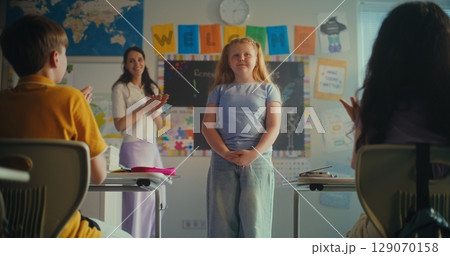 Shy Primary School Girl Showcasing Knowledge of Ecology in Front of Class and Teacher Shy Primary School Girl Showcasing Knowledge of Ecology in Front of Class and Teacher 129070158