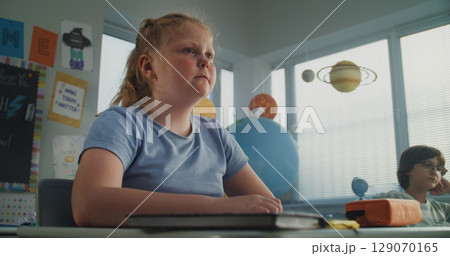 Stressed Primary School Girl Sitting at Desk While Classmates Abusing Her, Throwing Papers Stressed Primary School Girl Sitting at Desk While Classmates Abusing Her, Throwing Papers 129070165