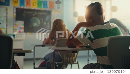 Elementary School Students Writing Exam in Modern Classroom. Female Teacher Controlling Test Process 129070194