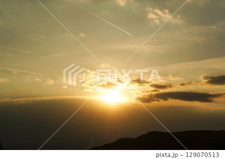 ところどころに雲がかかる夕暮れ時のオレンジ色に輝く空 129070513