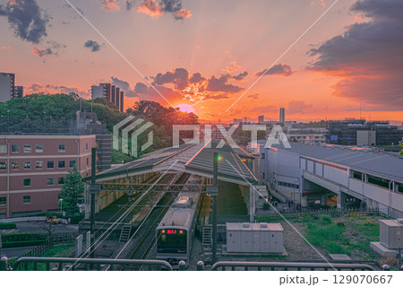 夕焼けの空と東京都多摩市の街を走る小田急線の電車 129070667