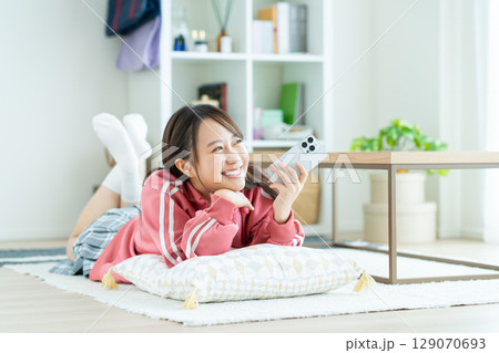 部屋でスマホを見る女子高生 129070693
