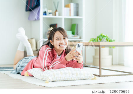 部屋でスマホを見る女子高生 129070695