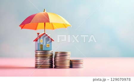 A small house with an umbrella sitting atop a mound of coins, representing the financial security that insurance provides 129070978