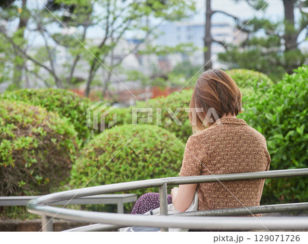夏の昼の公園のベンチで休憩する若い女性の姿 129071726