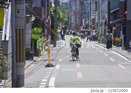 夏の京都の街で歩く人々と自転車を乗る女性の姿 129072000