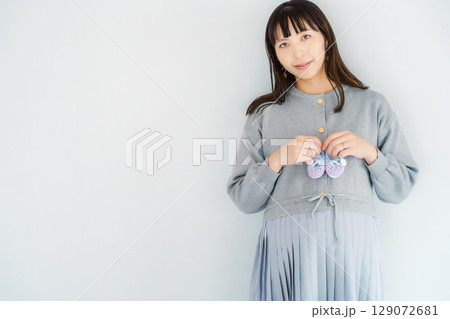 手編みのベビーシューズを持つ出産間近の妊婦 手編みのベビーシューズを持つ出産間近の妊婦 129072681