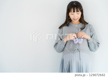 手編みのベビーシューズを持つ出産間近の妊婦 129072682