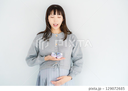 手編みのベビーシューズを持つ出産間近の妊婦 手編みのベビーシューズを持つ出産間近の妊婦 129072685
