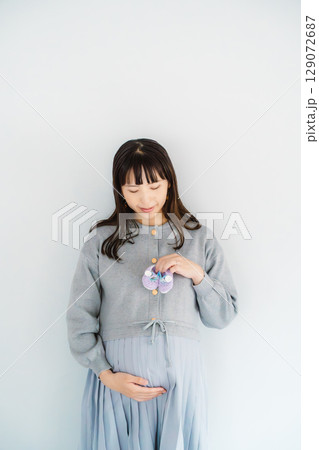 手編みのベビーシューズを持つ出産間近の妊婦 手編みのベビーシューズを持つ出産間近の妊婦 129072687