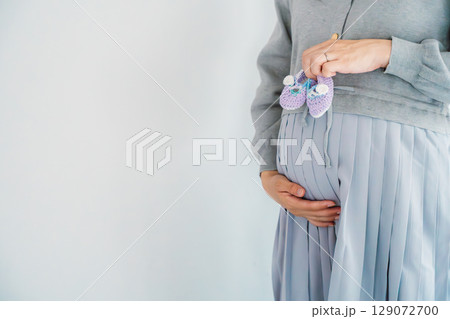 手編みのベビーシューズを持つ出産間近の妊婦 129072700