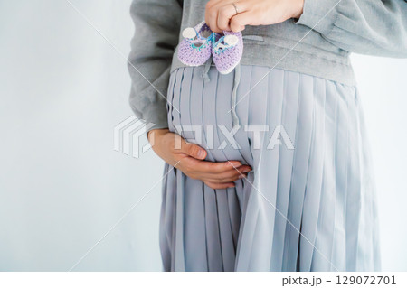 手編みのベビーシューズを持つ出産間近の妊婦 手編みのベビーシューズを持つ出産間近の妊婦 129072701