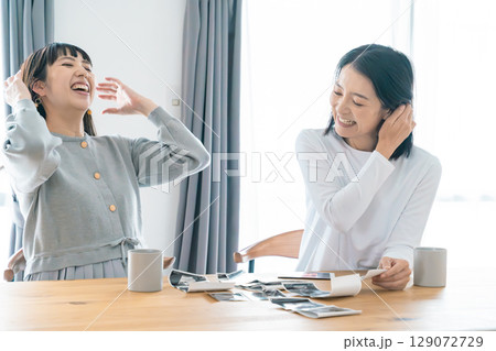 リビングでエコー写真を見ながら赤ちゃんが生まれてくるのを待ち望んでいる母と娘 リビングでエコー写真を見ながら赤ちゃんが生まれてくるのを待ち望んでいる母と娘 129072729