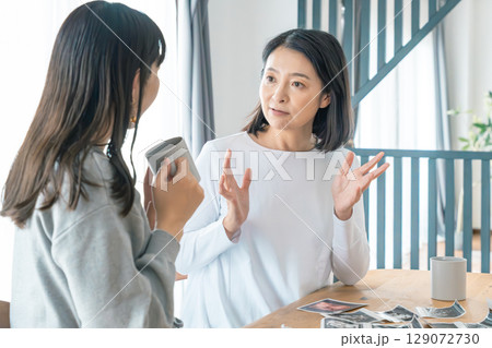 リビングでエコー写真を見ながら赤ちゃんが生まれてくるのを待ち望んでいる母と娘 リビングでエコー写真を見ながら赤ちゃんが生まれてくるのを待ち望んでいる母と娘 129072730
