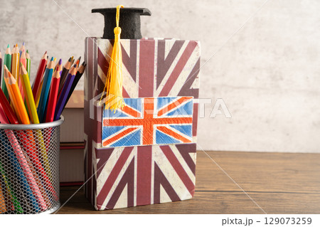 UK flag with graduate hat on english language book. UK flag with graduate hat on english language book. 129073259