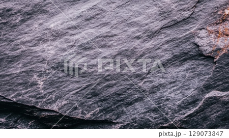 Textured surface of gray rock showcasing natural patterns in a rugged outdoor setting during daylight hours 129073847