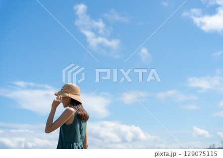 青い海に立つ若い女性 129075115