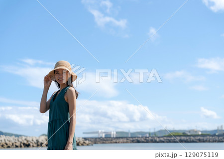 青い海に立つ若い女性 129075119