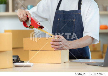 E-commerce Packaging. Employee applying tape to boxes for efficient shipping process. E-commerce Packaging. Employee applying tape to boxes for efficient shipping process. 129077829