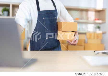 E-commerce Success. Young man managing packages in online business environment. 129077830