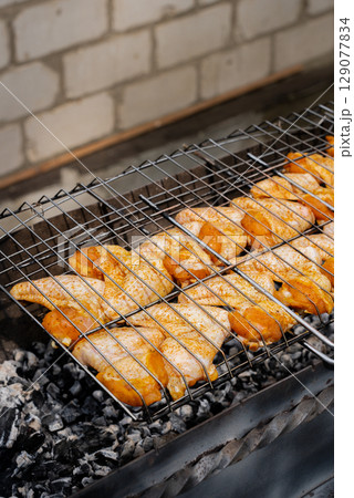 BBQ picnic time Roasted chicken legs and wings on grill. Grilling meat on outdoor grill grid tasty barbeque chicken steak with smoke flames juicy meat in the backyard 129077834