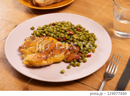Appetizing crispy chicken with peas as side dish on plate 129077880