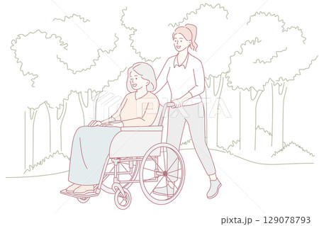 A caregiver assists an elderly woman in her wheelchair outdoors, fostering a joyful atmosphere 129078793