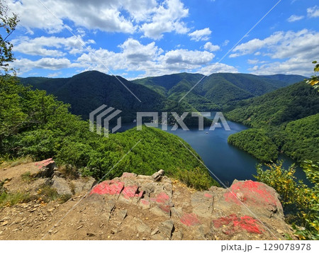 View from Piatra lui Lucaci over the Tarnita lake and forest mountains on a beautiful summer day with blue sky and white clouds. Cluj, Romania View from Piatra lui Lucaci over the Tarnita lake and forest mountains on a beautiful summer day with blue sky and white clouds. Cluj, Romania 129078978