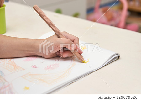 Child drawing with colored pencil on sketchpad creating colorful star patterns Child drawing with colored pencil on sketchpad creating colorful star patterns 129079326