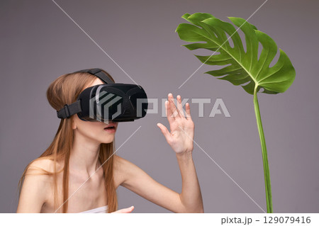 Young caucasian female using virtual reality headset interacting with plant 129079416