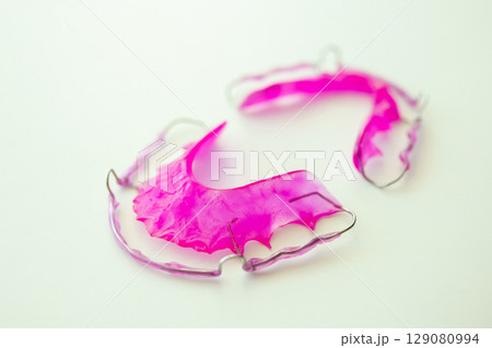Pink acrylic dental retainer on white background 129080994
