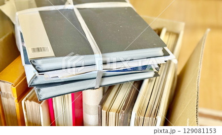 箱に入ったたくさんのアルバムとその上に乗せた書類ファイル 箱に入ったたくさんのアルバムとその上に乗せた書類ファイル 129081153