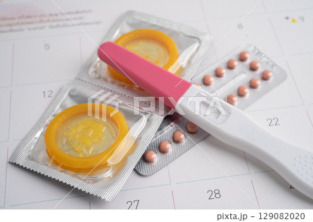 Pregnancy test and condom for female on calendar, ovulation day. 129082020