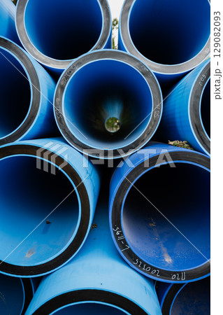 Blue PVC pipes stacked in a circular arrangement showcasing industrial materials and textures Blue PVC pipes stacked in a circular arrangement showcasing industrial materials and textures 129082093