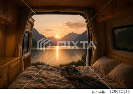 Cozy camper interior with scenic mountain view at sunset reflecting on tranquil lake 129082120