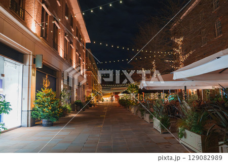 A tranquil London street during Christmas, featuring glowing lights, decorated buildings, and Christmas trees, creating a peaceful holiday atmosphere. 129082989