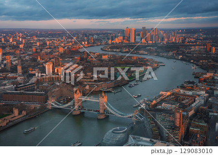 The image shows an aerial view of London with Tower Bridge in the foreground and Canary Wharf in the background during the Christmas period. 129083010