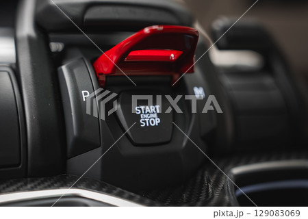 Detailed view of the Lamborghini Urus center console showing the red flip cover over the Start Engine Stop button, carbon fiber, and gear buttons. 129083069