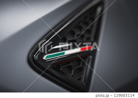 Detailed view of a Lamborghini Urus air vent featuring a black honeycomb grille, Italian flag emblem, and matte gray surface highlighting craftsmanship. 129083114