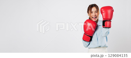 Boxing lifestyle meets confidence as Asian young woman smiles in red gloves. Business-driven and fight-ready, she shows strong guard and red boxing power. isolated studio white background Boxing lifestyle meets confidence as Asian young woman smiles in red gloves. Business-driven and fight-ready, she shows strong guard and red boxing power. isolated studio white background 129084135
