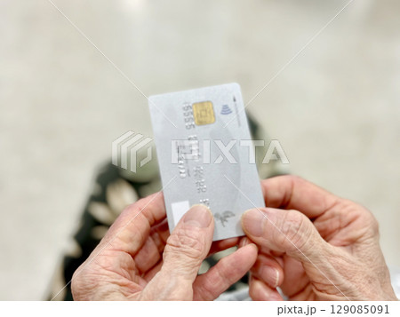 クレジットカードを持つ高齢者の両手の指 クレジットカードを持つ高齢者の両手の指 129085091